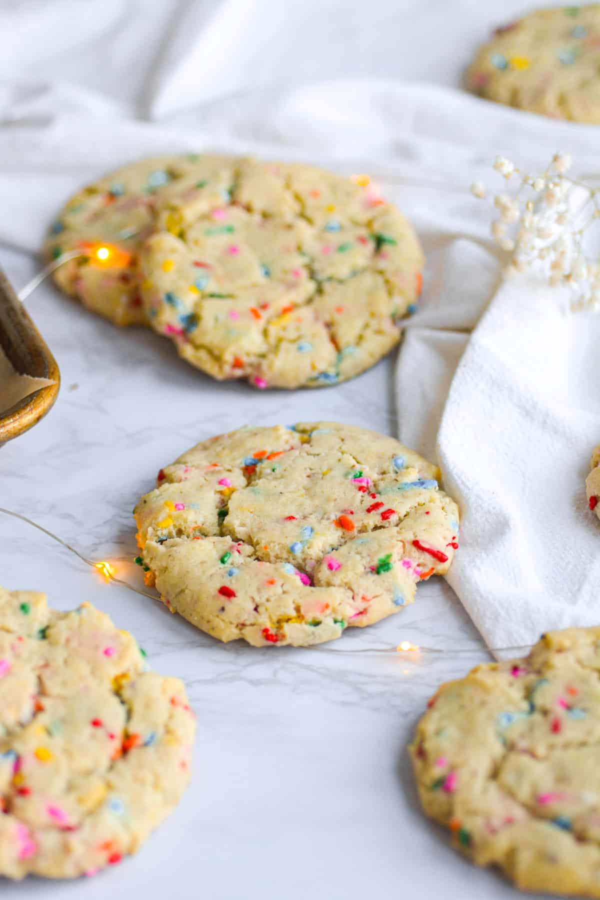 vegan funfetti cookies on a marble board with a white cloth in the background