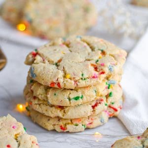 four vegan funfetti cookies stacked on a marble board