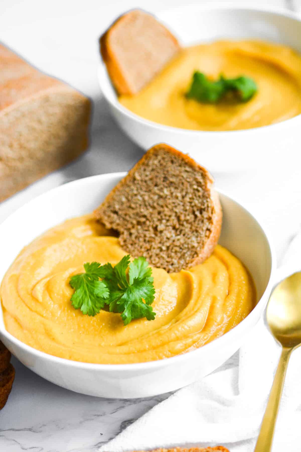 two bowls of cauliflower red lentil soup on a marble board