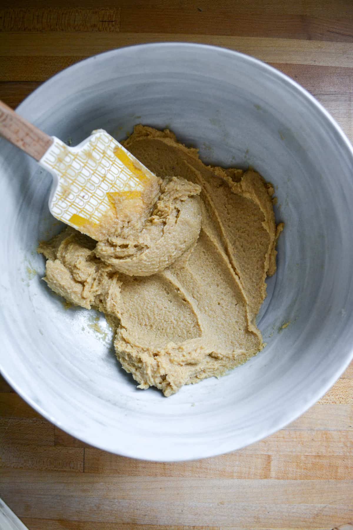 Overhead shot of vegan butter and brown sugar creamed together in a marble bowl with a spatula in it.