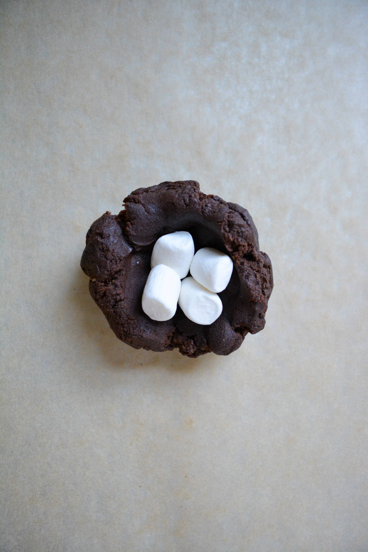 Marshmallows in the well of a dark chocolate cookie dough mound.