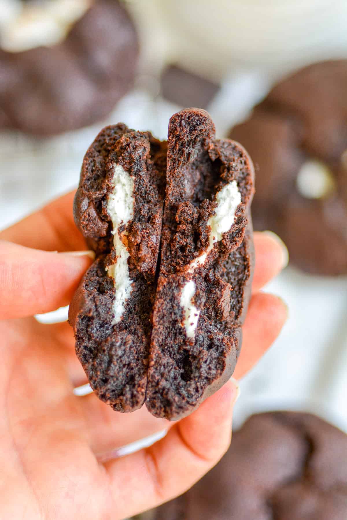 A hand holding a broken open Dark Chocolate Marshmallow cookie
