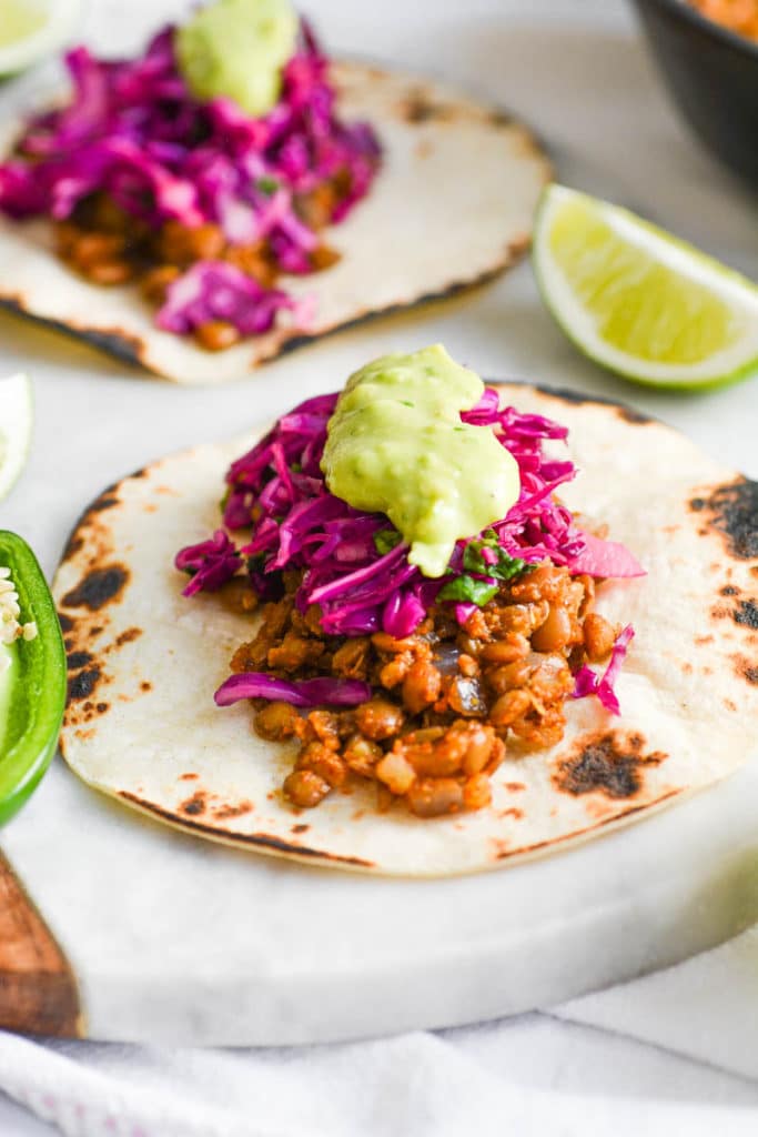 a taco on a marble board with lentil taco filling and red cabbage slaw