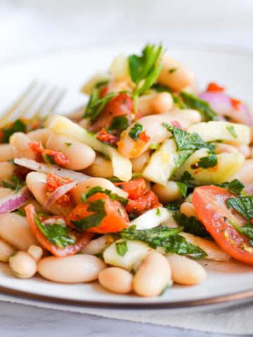 Landscape of Italian White Bean Salad on a tan plate with a gold fork