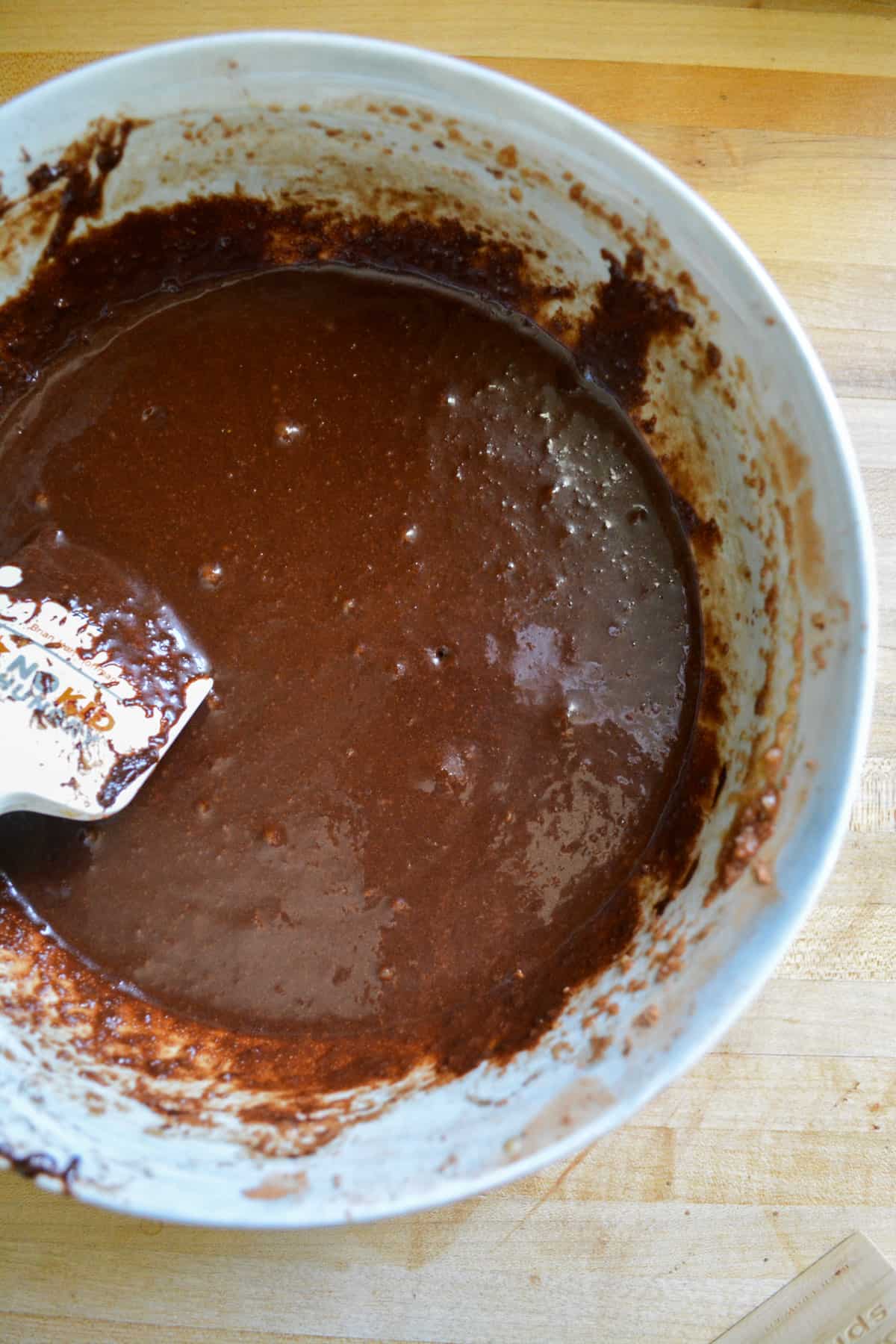 Apple sauce added to the chocolate batter in a mixing bowl.