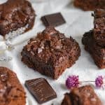 brownies on a white cloth with flowers and chocolate chunks in the foreground