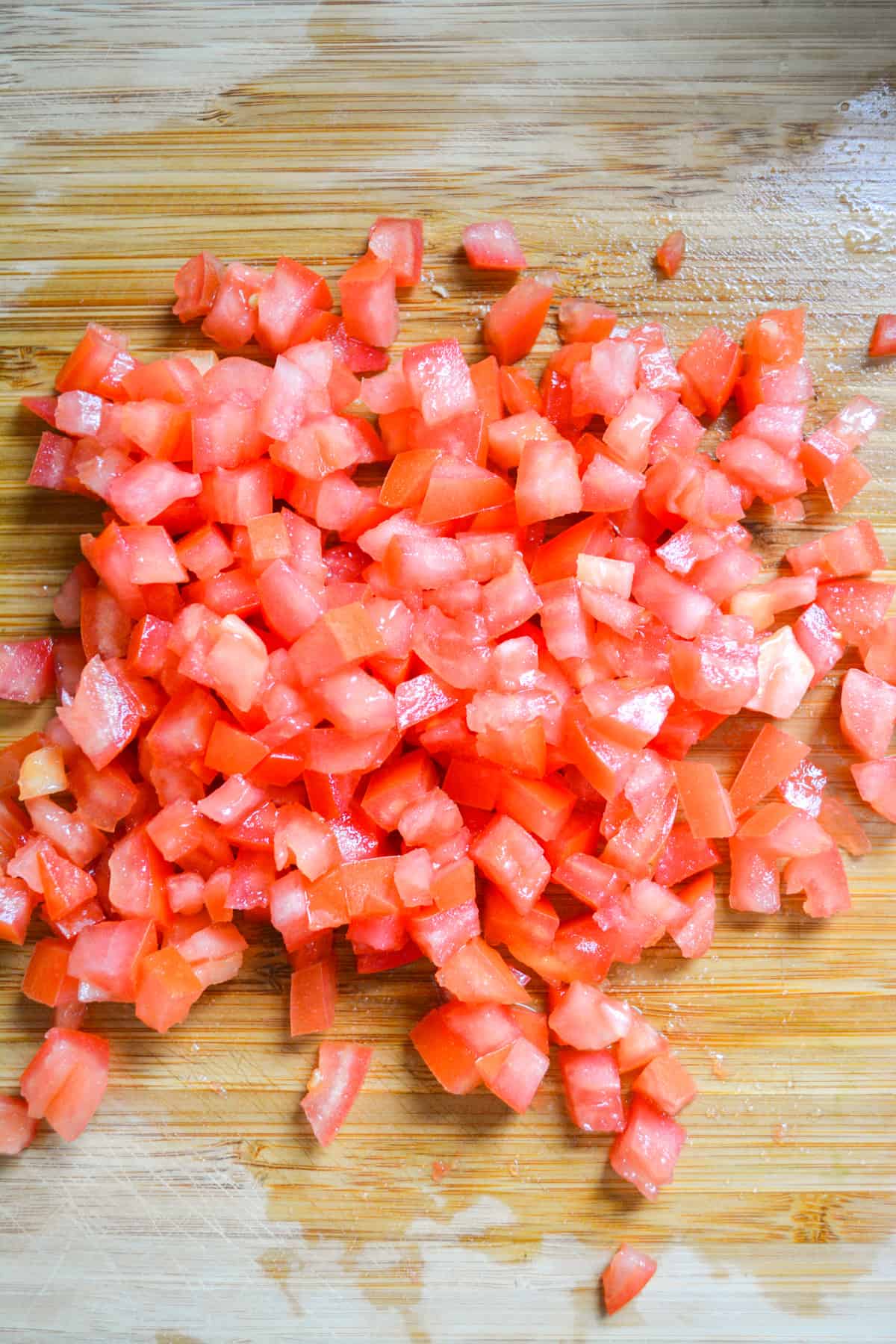 Diced Roma tomatoes on a wooden cutting board.