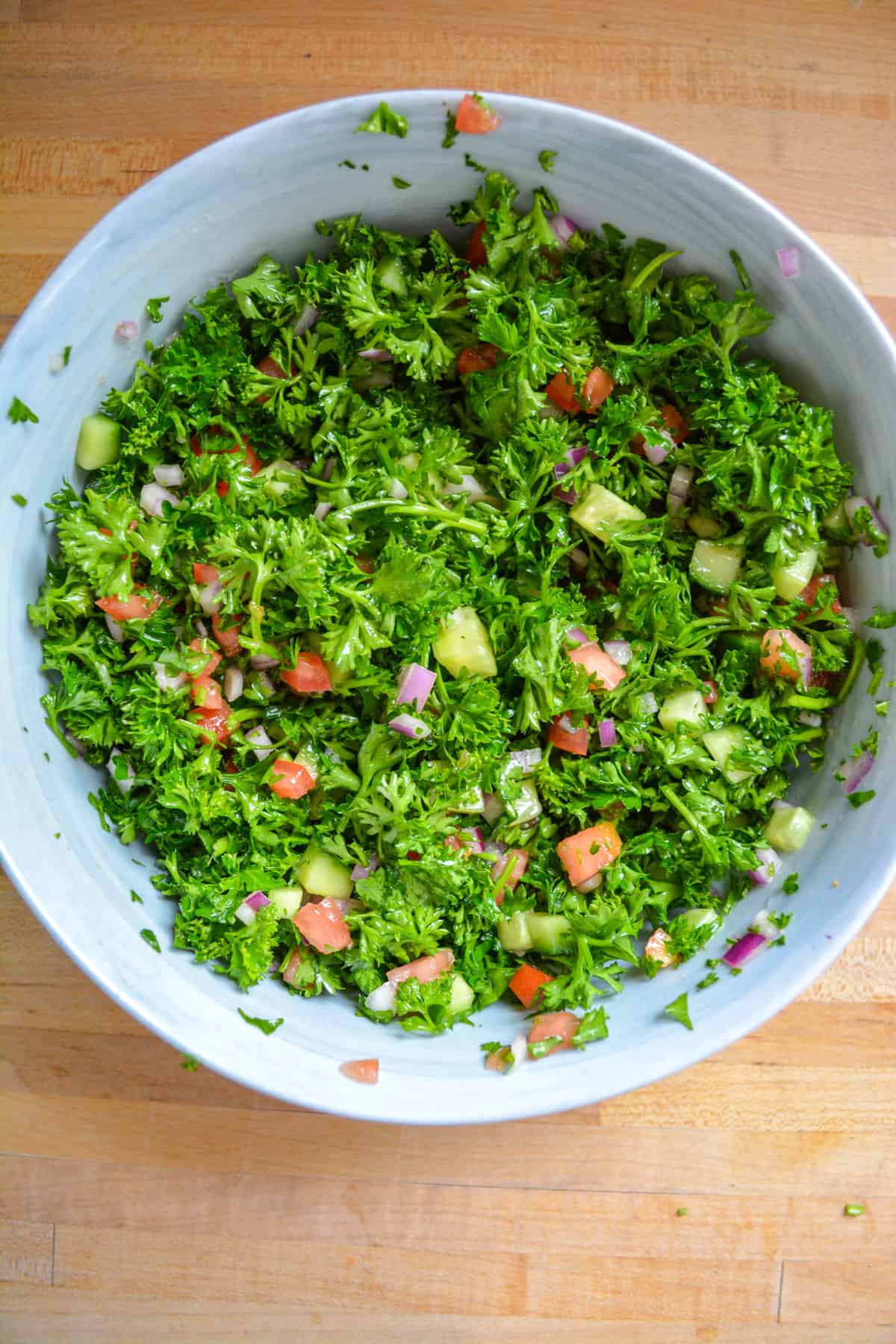 The tabouli salad recipe all tossed together in a mixing bowl.