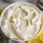 Vegan Lemon Buttercream Frosting in a white bowl with lemon in the foreground.
