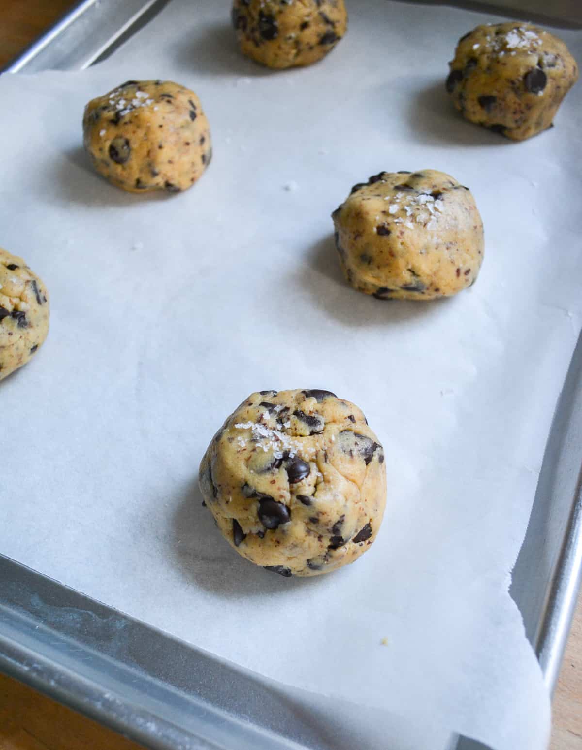 cookie dough balls on a parchment lined sheet tray