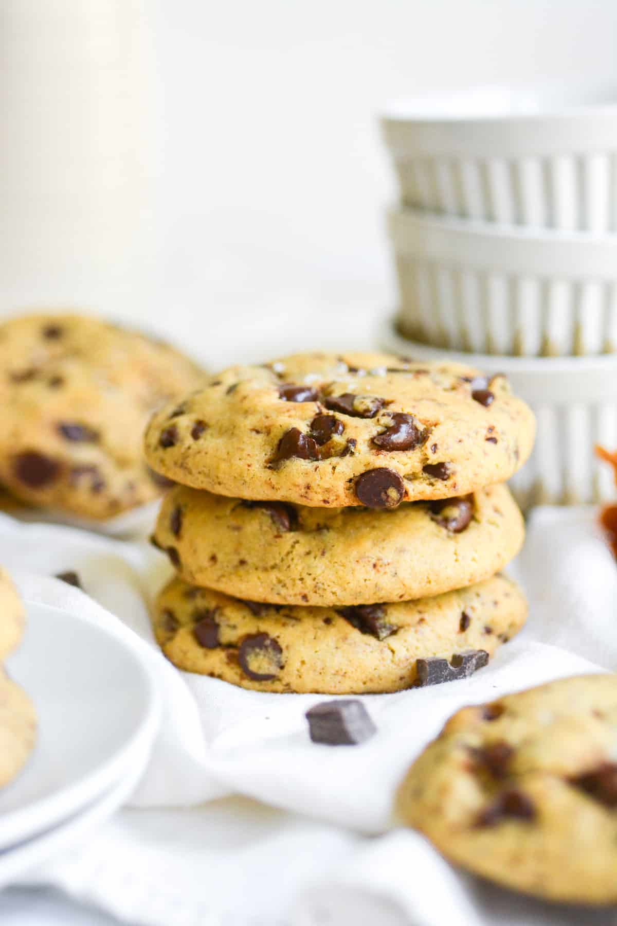 Three Vegan Levain cookies stacked on top of each other on a white cloth