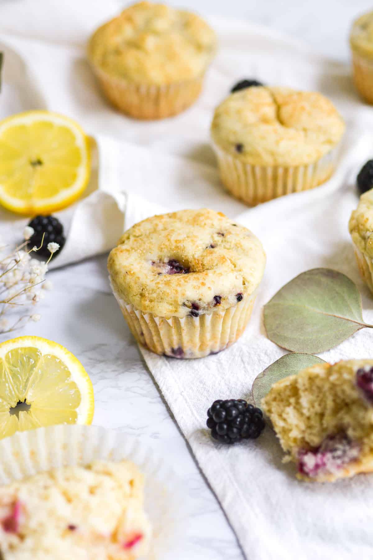 Muffins on a marble board with lemon slices and blackberries in the background