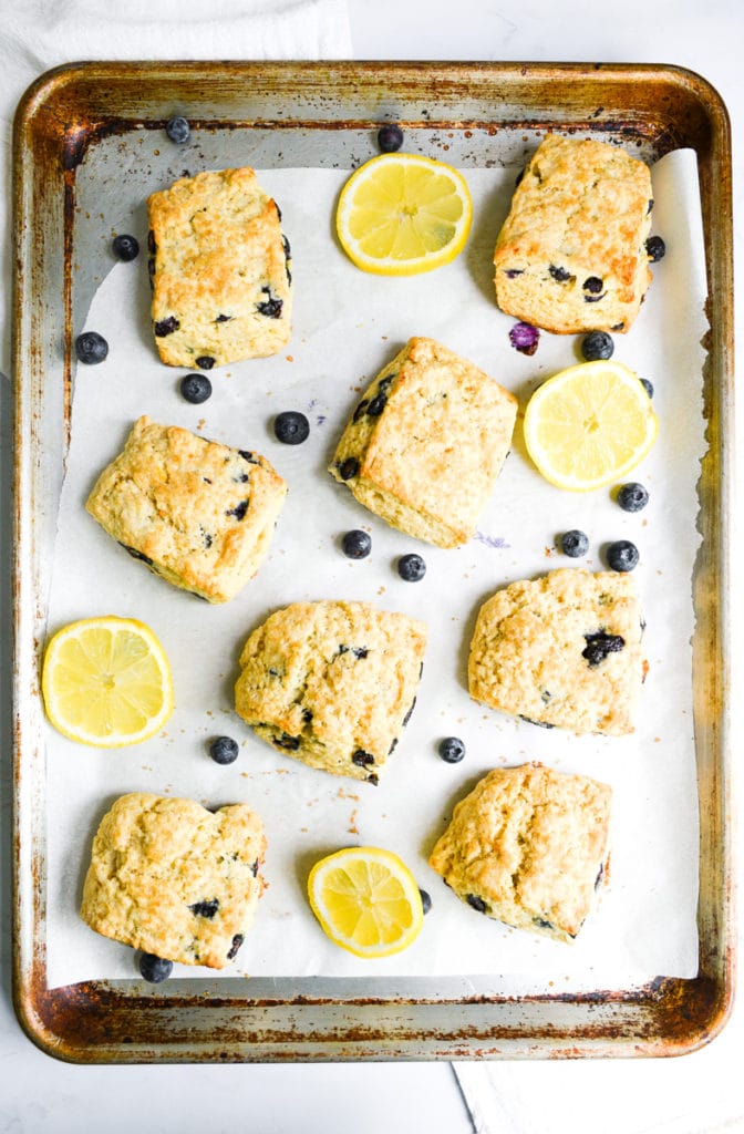 Eggless scones on a baking sheet with blueberies and lemon slices
