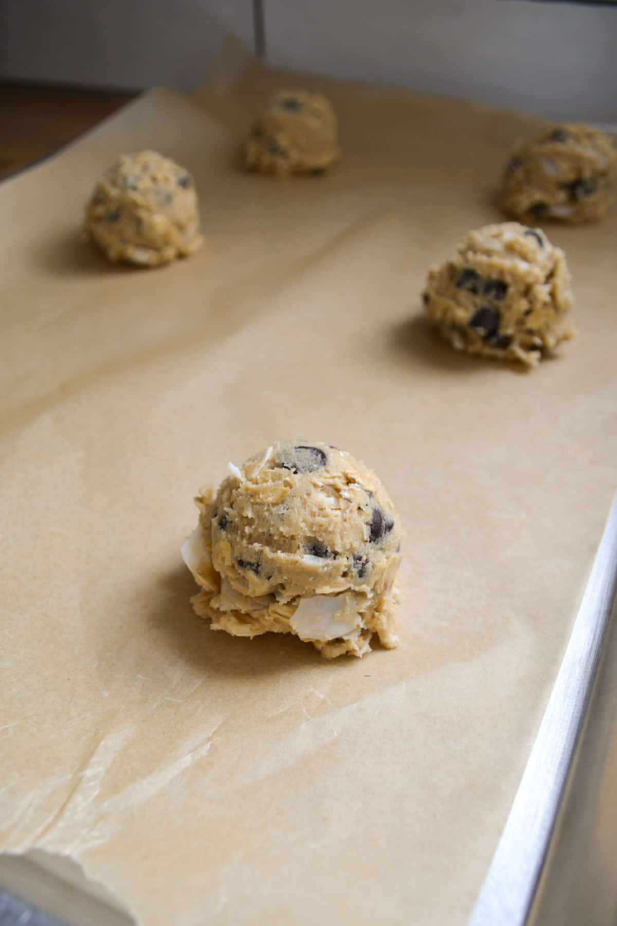 Vegan Oatmeal Coconut Chocolate Chip Cookie dough scooped onto a baking sheet.