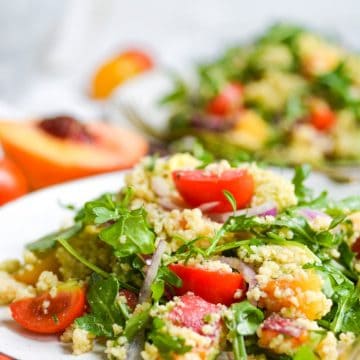 two plates of salad with peaches, tomatoes and arugula