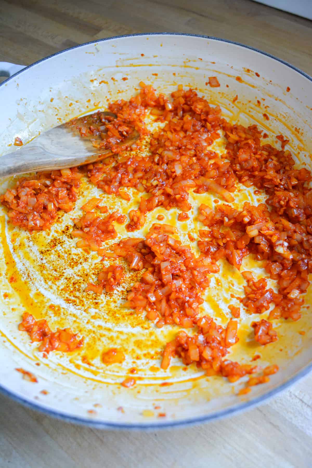 Tomato paste added into the onion and garlic in a wide shallow skillet.