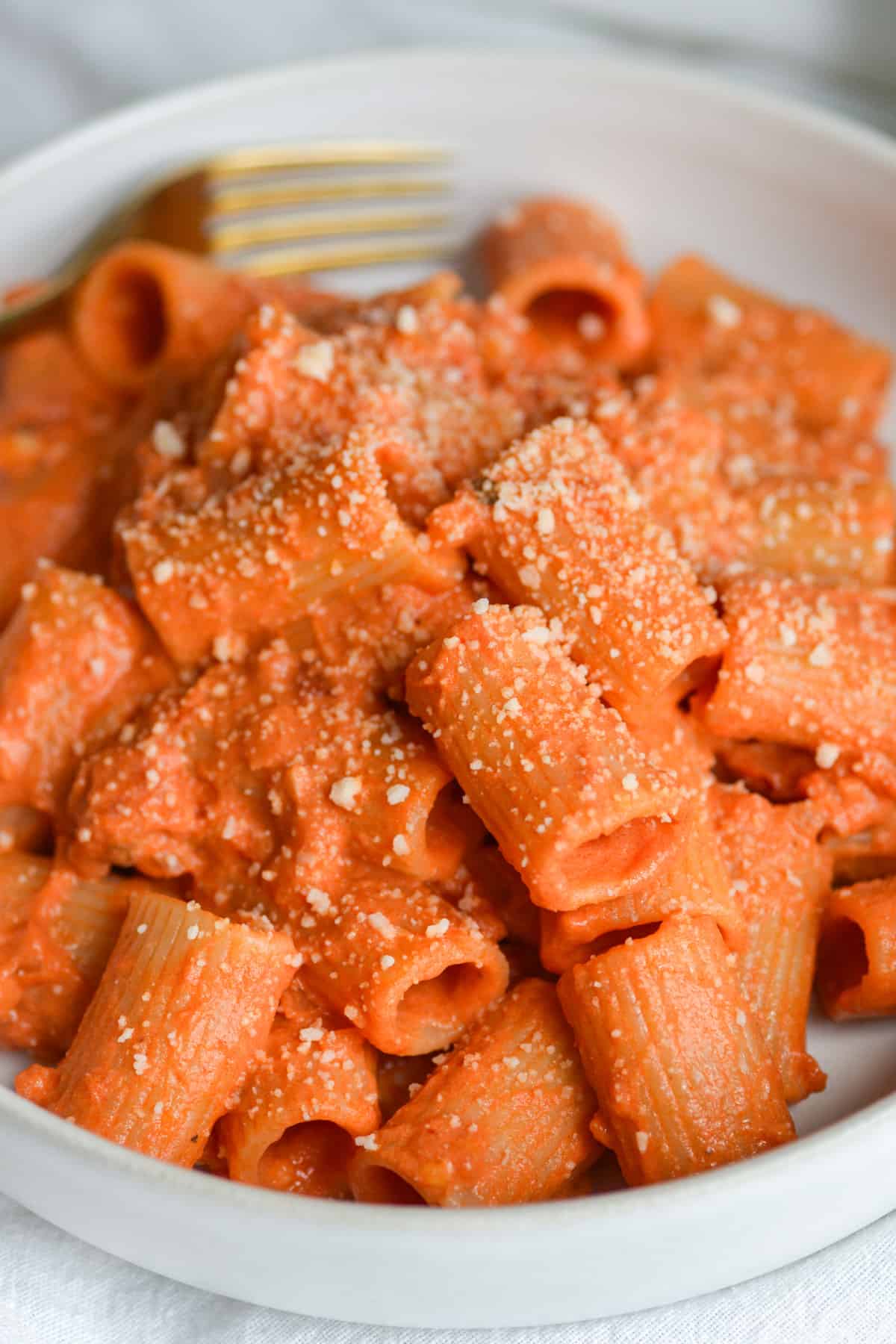 Vegan Dairy-Free Vodka Sauce with pasta in a bowl topped with a sprinkle of vegan parmesan. 