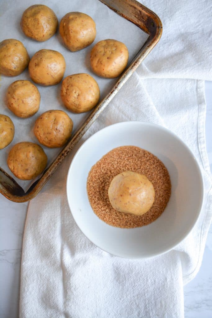 A dough ball in a bowl of turbinado sugar