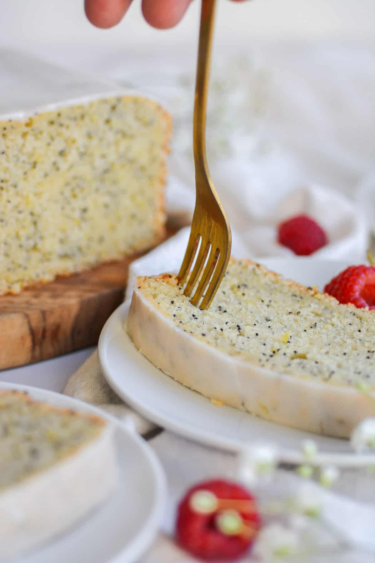 Gold fork in a slice of vegan lemon poppy seed loaf cake