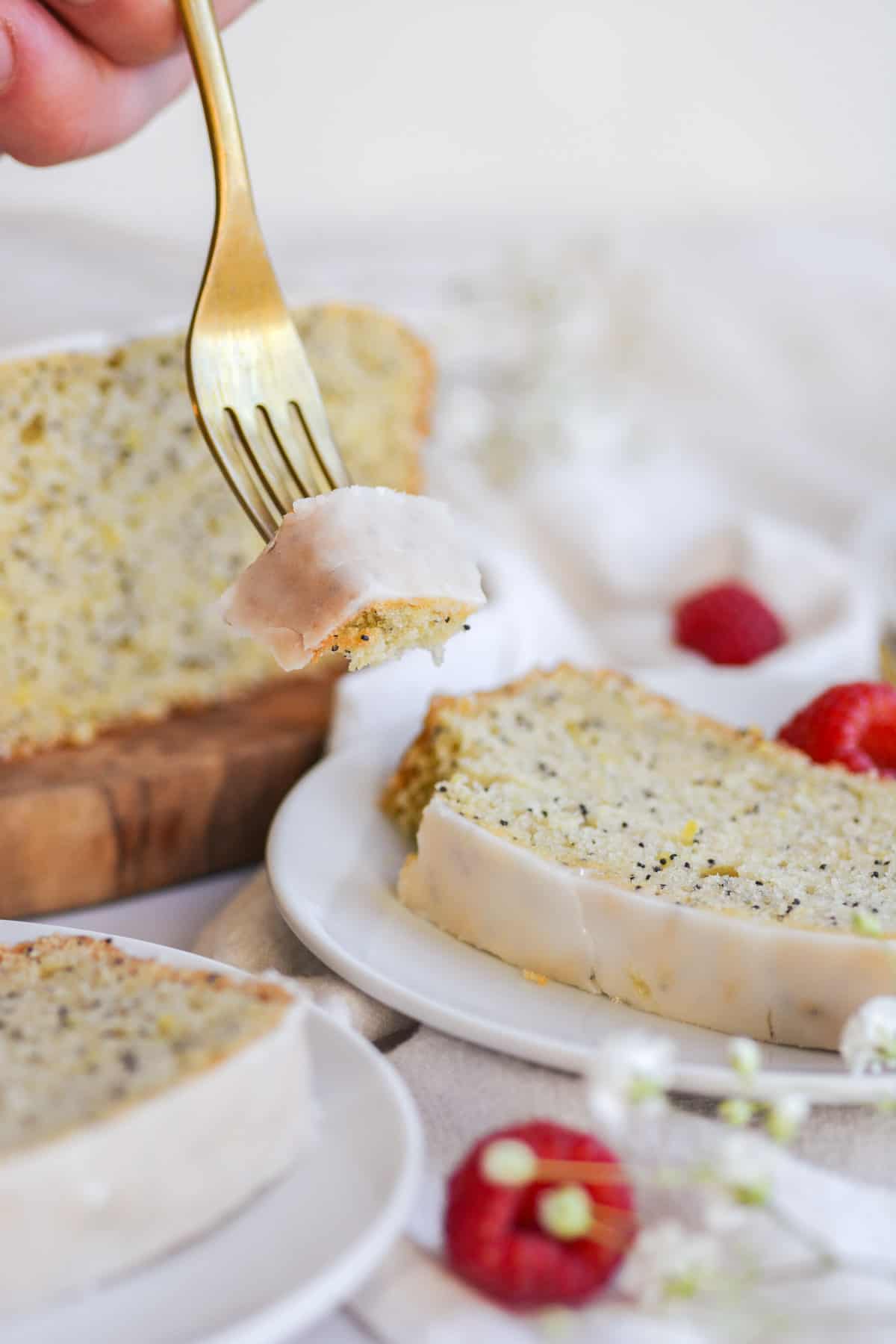 A bite of vegan lemon poppyseed loaf cake on a gold fork