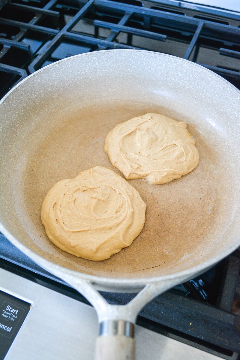 Two pancakes cooking on a skillet.