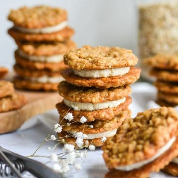 Portrait of stacked Vegan Oatmeal Cream pies on a white board with more cookies in the background