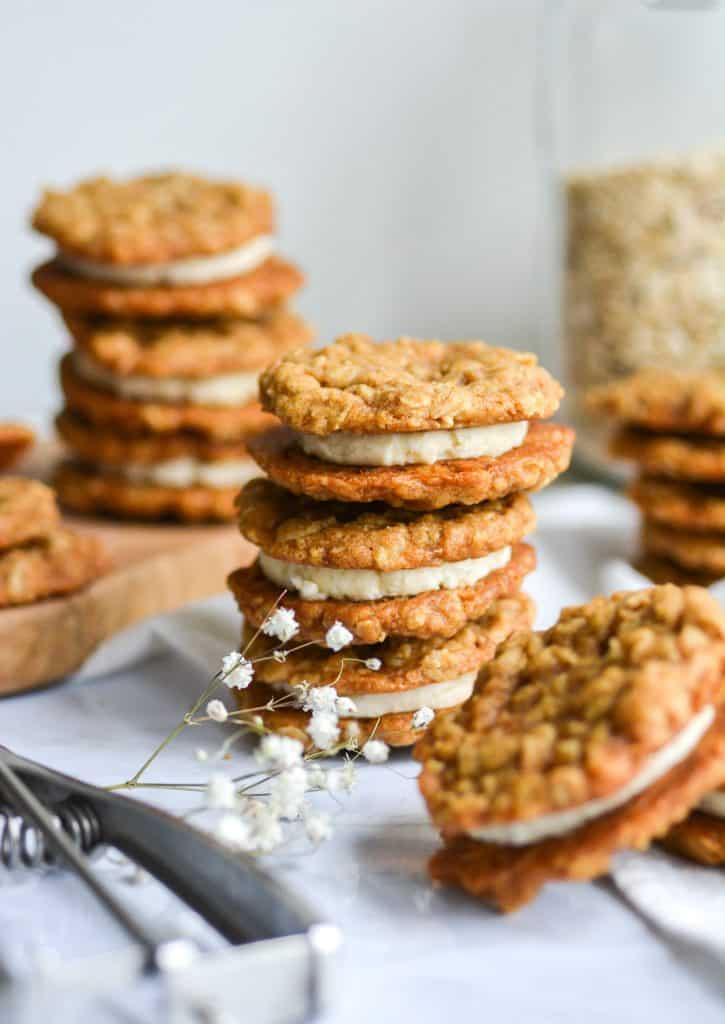 Portrait of stacked Vegan Oatmeal Cream pies on a white board with more cookies in the background