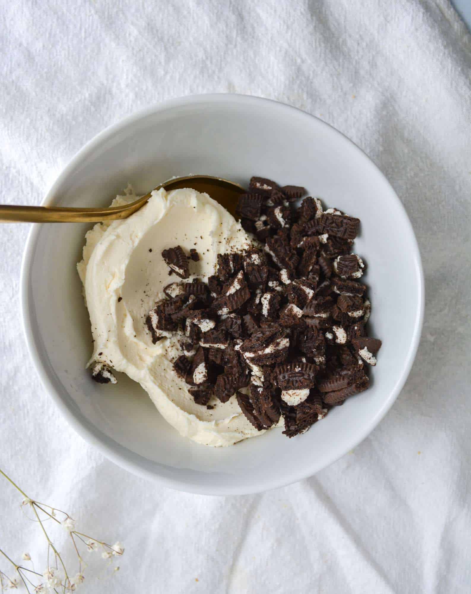 chopped oreos and vanilla buttercream in a white bowl