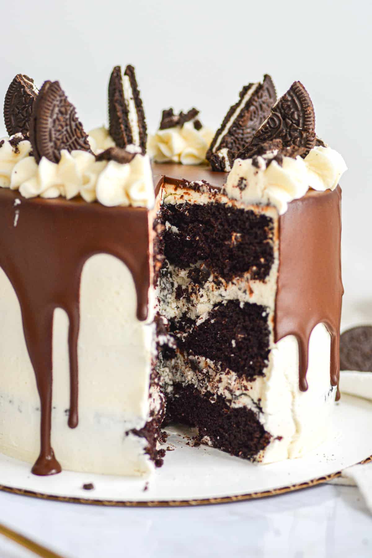 Vegan Oreo Drip Cake with a slice taken out of it so you can see the chocolate cake layers and Oreo buttercream.