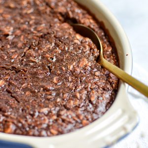 Chocolate Baked Oatmeal in a baking dish with a gold spoon