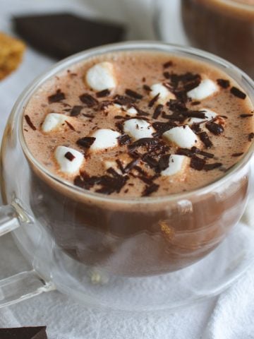 Vegan Oatmilk Hot Chocolate in a glass mug topped with marshmallows and shaved chocolate