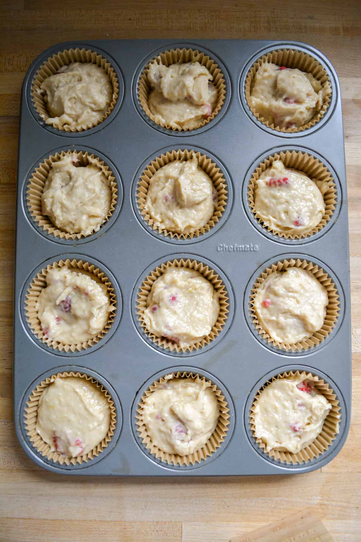 Raspberry muffin batter scooped into a lined muffin tin.