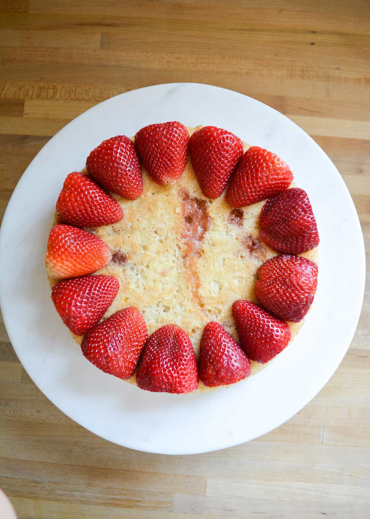 Strawberries lining the perimeter of a cake layer