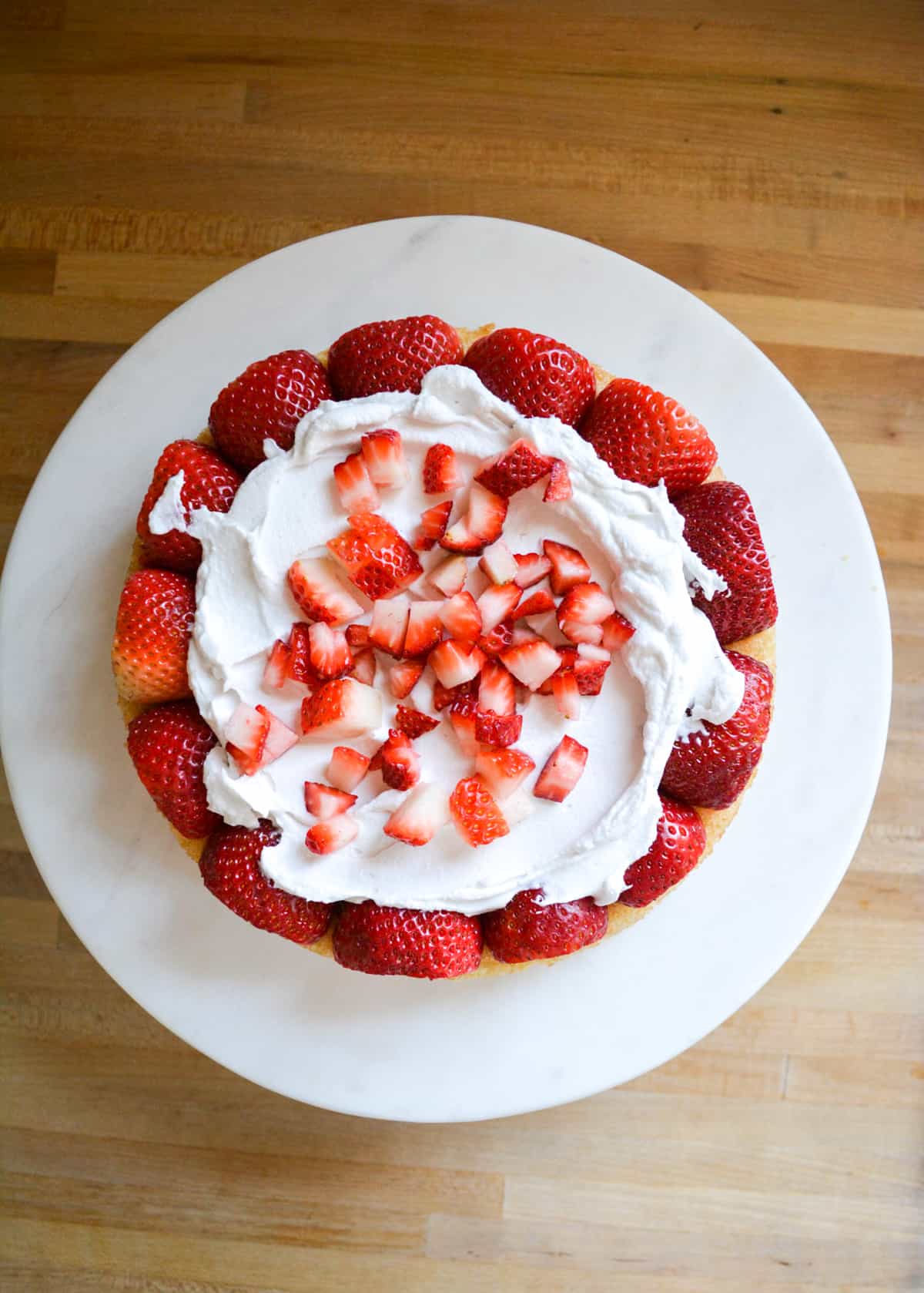 topping the whipped cream filling with chopped strawberries