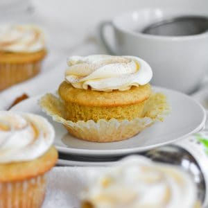 cardamom cupcake with vanilla buttercream on a white plate with the wrapper removed