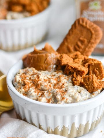 A ramekin filled with Biscoff overnight oats with cookie butter and biscoff cookis on top