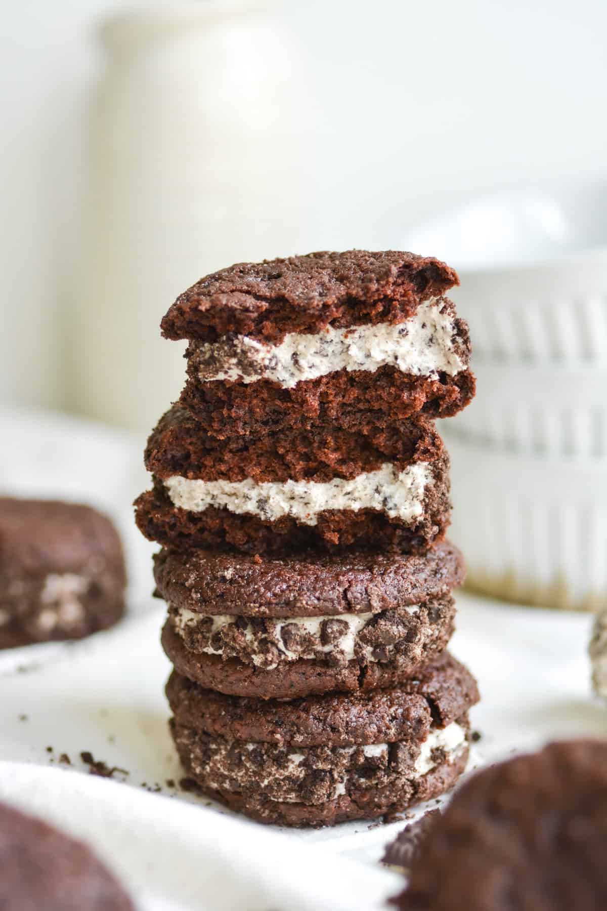 A stack of vegan oreo whoopie pies with one broken open to show the middle