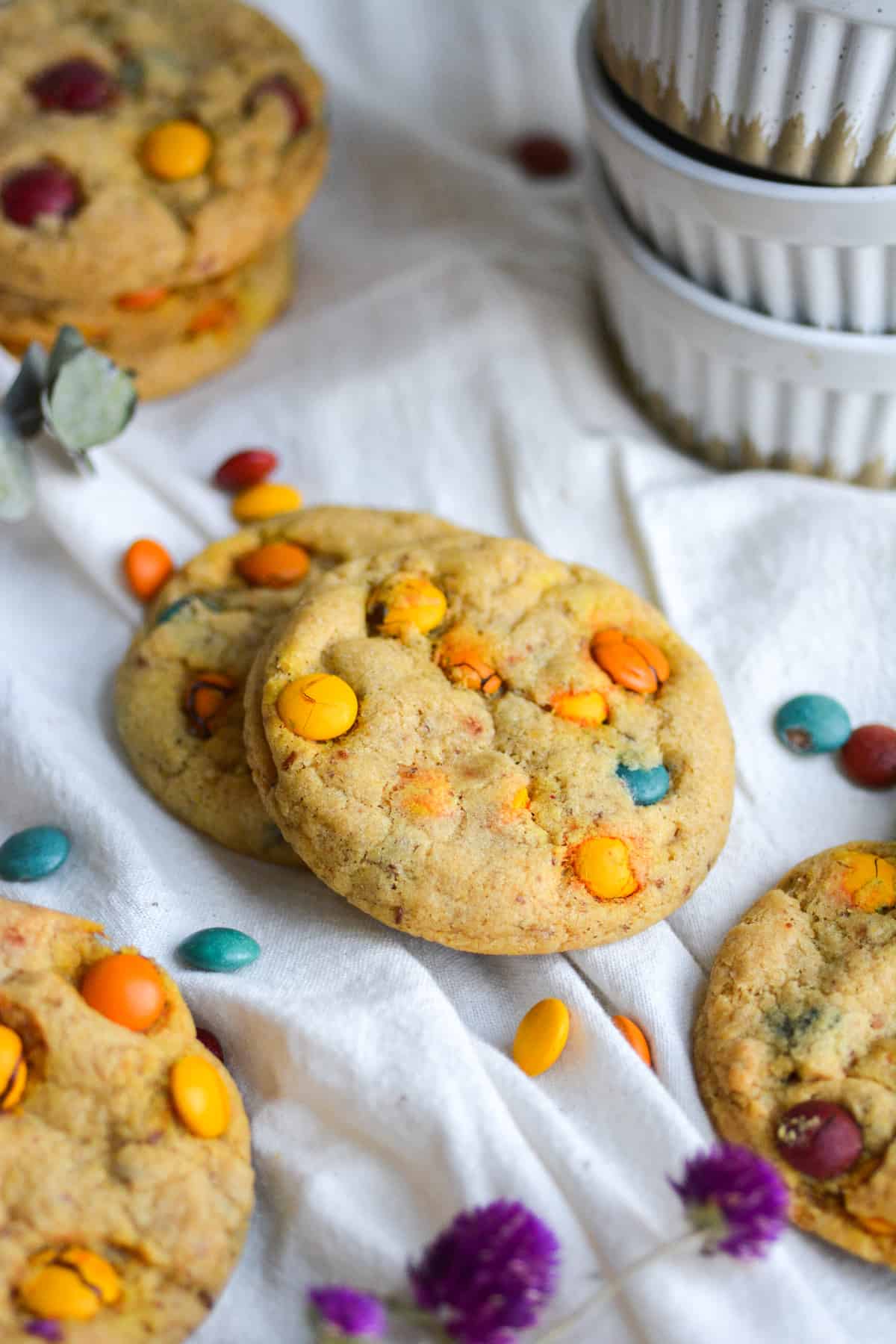 Vegan M&M Cookies on a white cloth with M&Ms scattered around