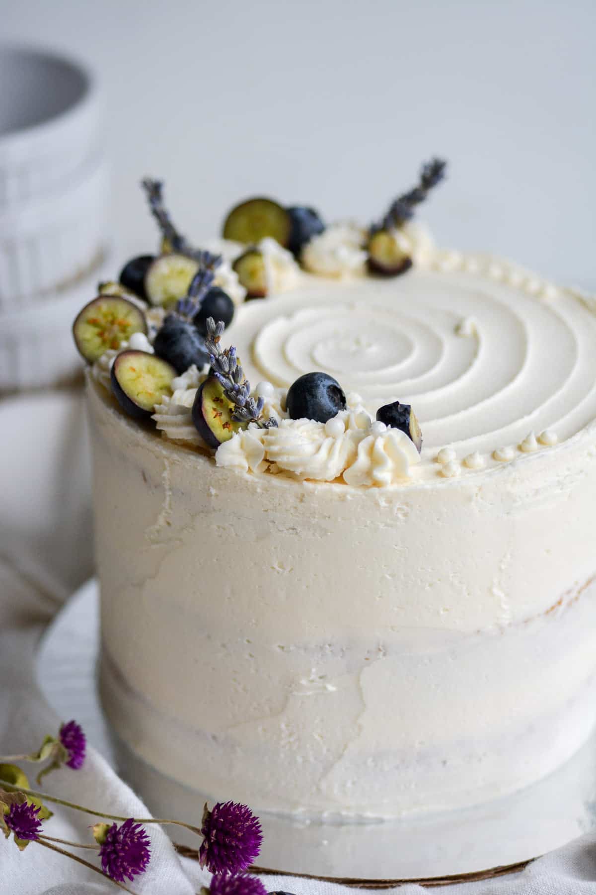Blueberry jam cake frosted with vanilla buttercream decorate with blueberries and lavender flowers