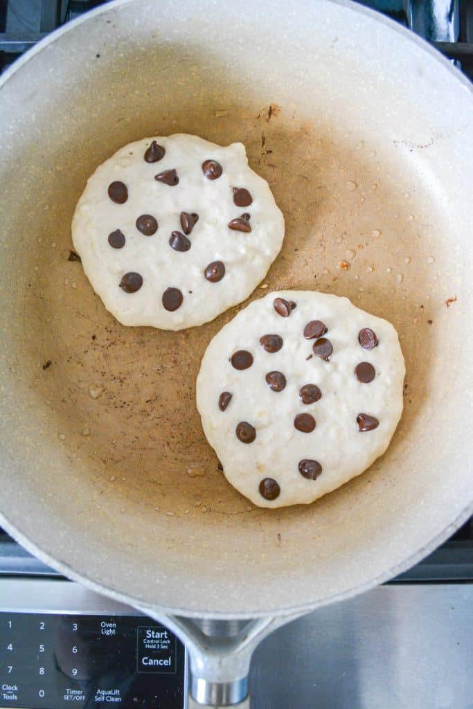 Vegan oat milk pancakes with chocolate chips cooking in a skillet