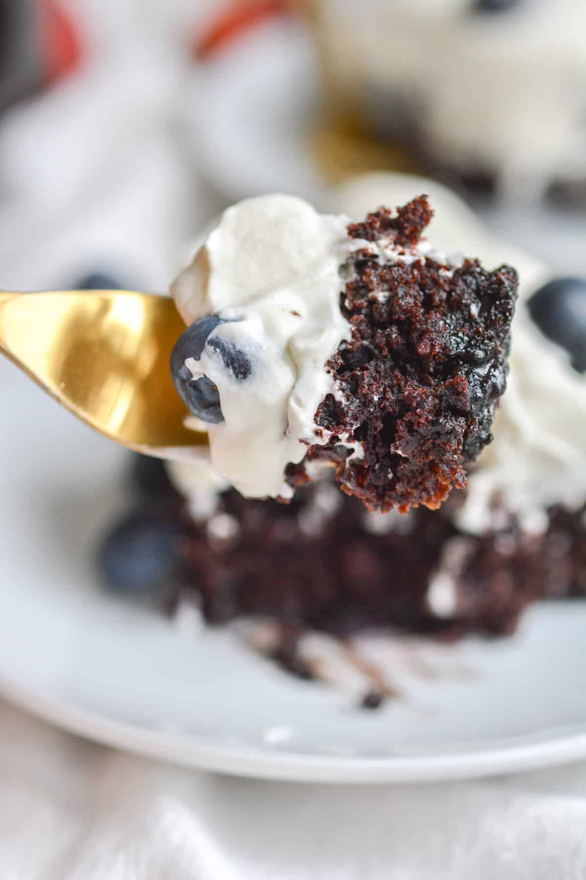 a bite of vegan chocolate blueberry cake on a gold fork