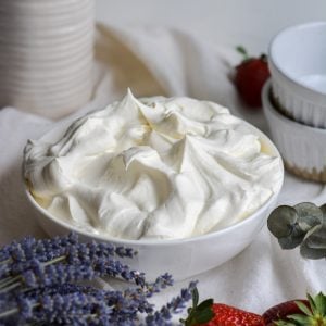 Vegan Whipped Cream Frosting in a bowl with strawberries in the foreground