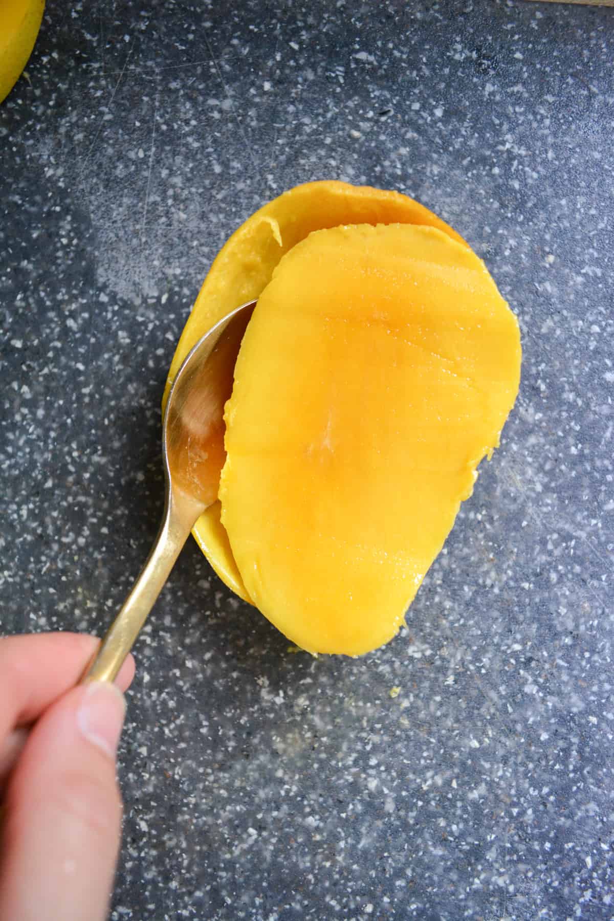 Spoon scooping mango away from its peel