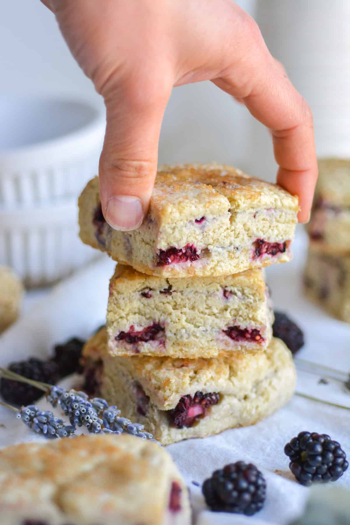 Hand placing a gluten free vegan scone on top of a stack