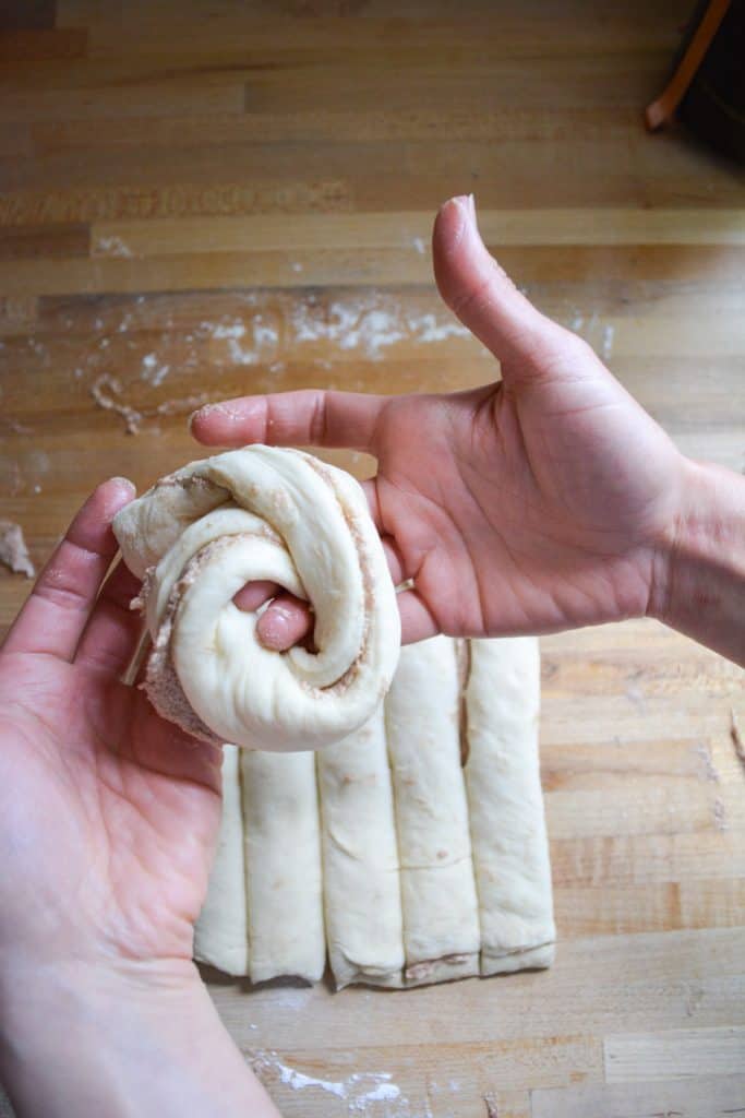 hands demonstrating how to shape a vegan honey bun