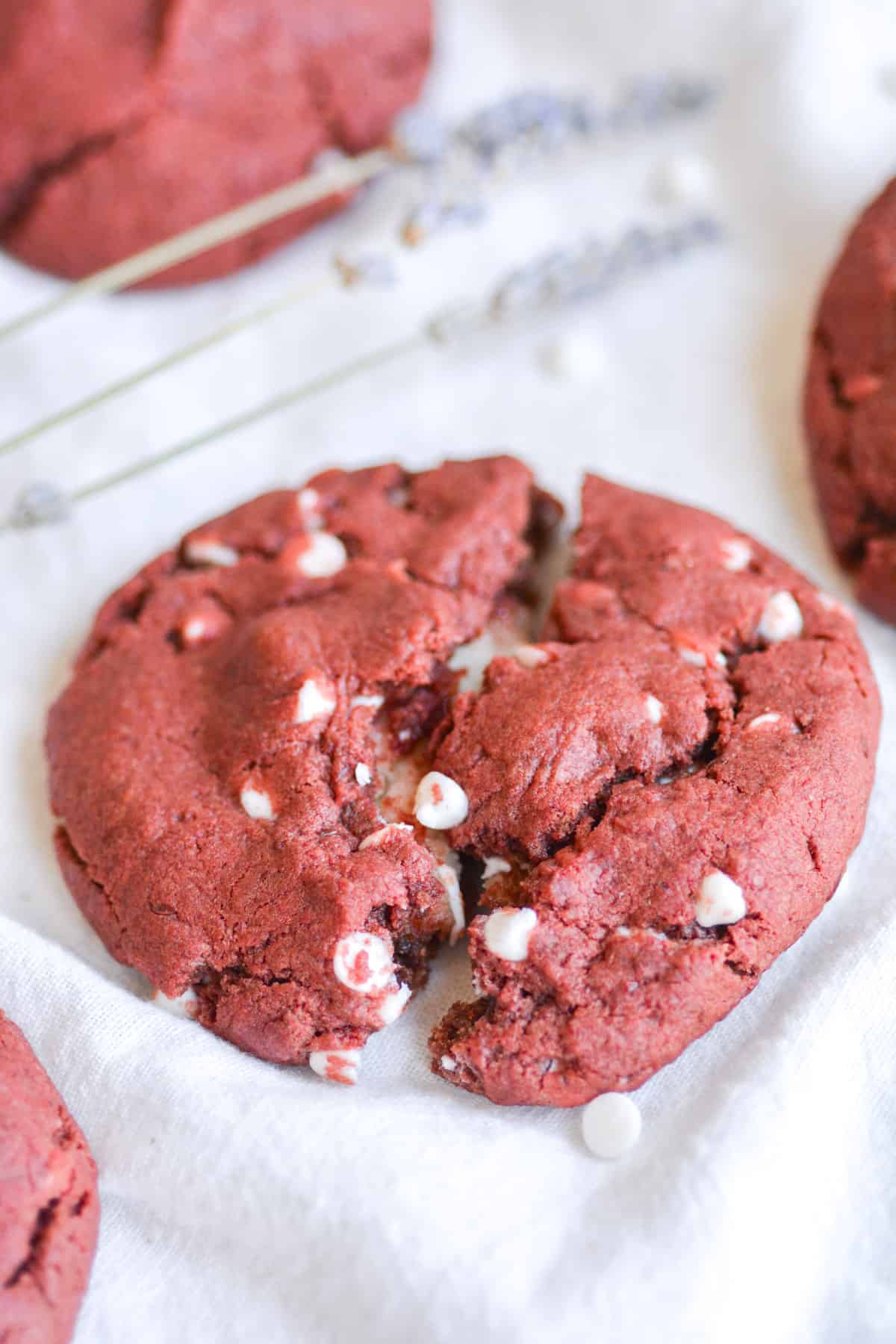 A vegan red velvet cookie with cream cheese filling on a white cloth