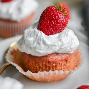 Close up of a strawberry and cream cupcake on a white cloth