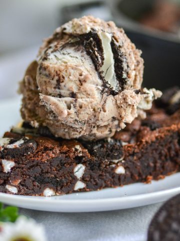 Vegan oreo pizookie on a white plate with a scoop of ice cream on top