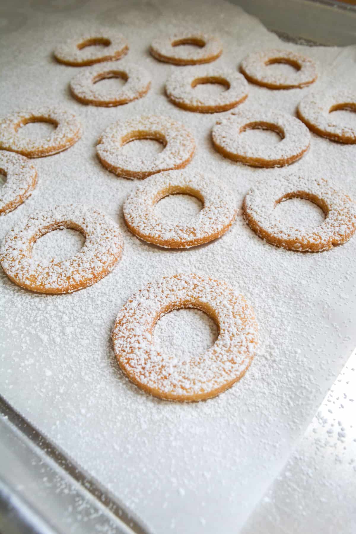 Baked nut-free vegan linzer cookie tops, dusted with powdered sugar.