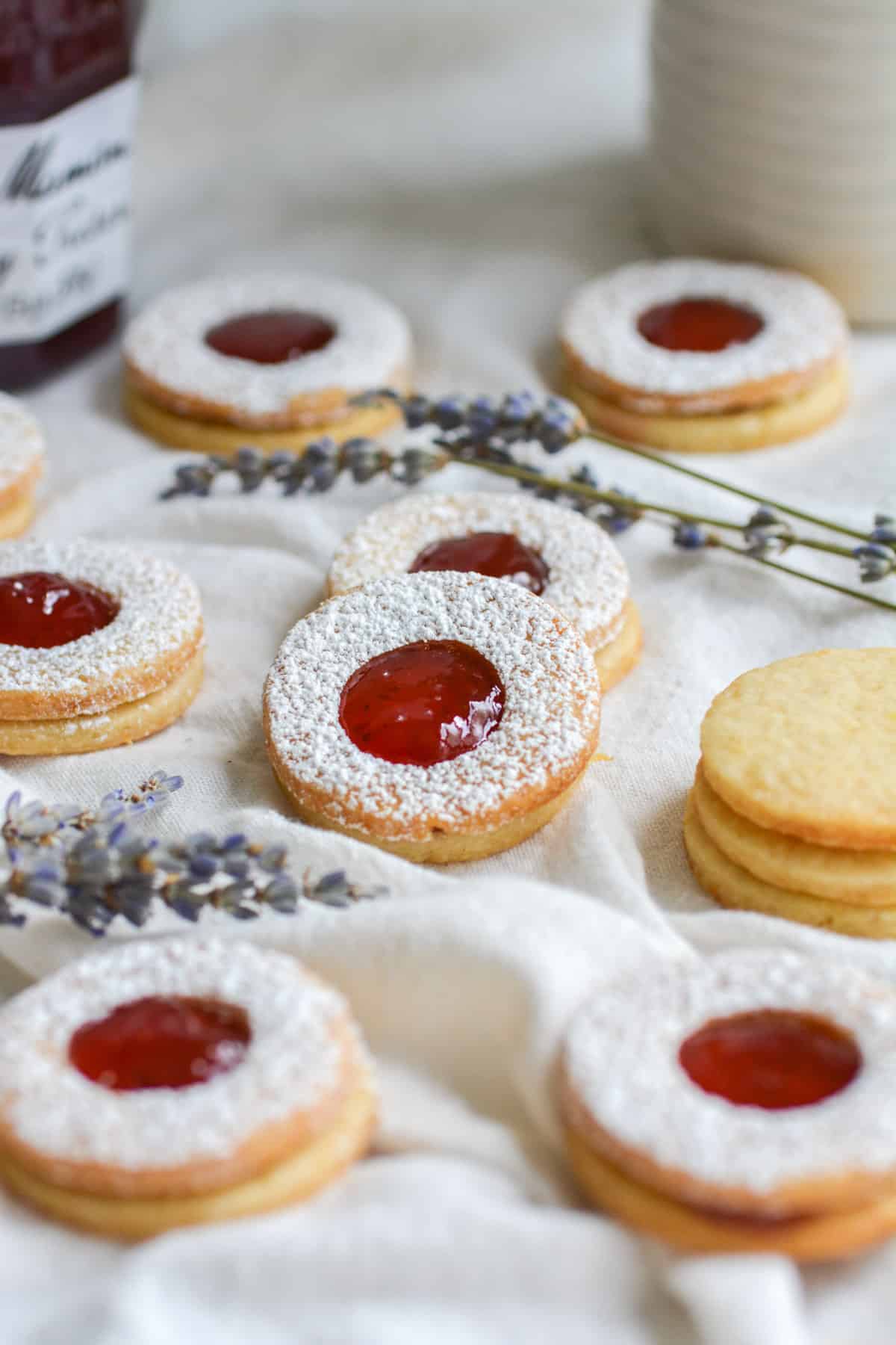 Vegan Nut Free Linzer Cookies filled with strawberry jam on a white cloth.